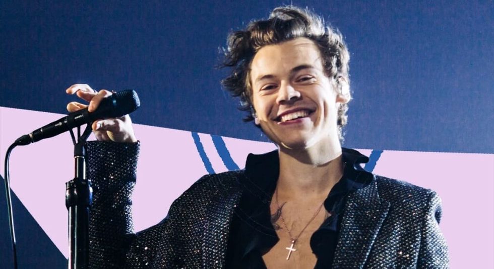 Harry Stles in all black with cross necklace on stage preforming