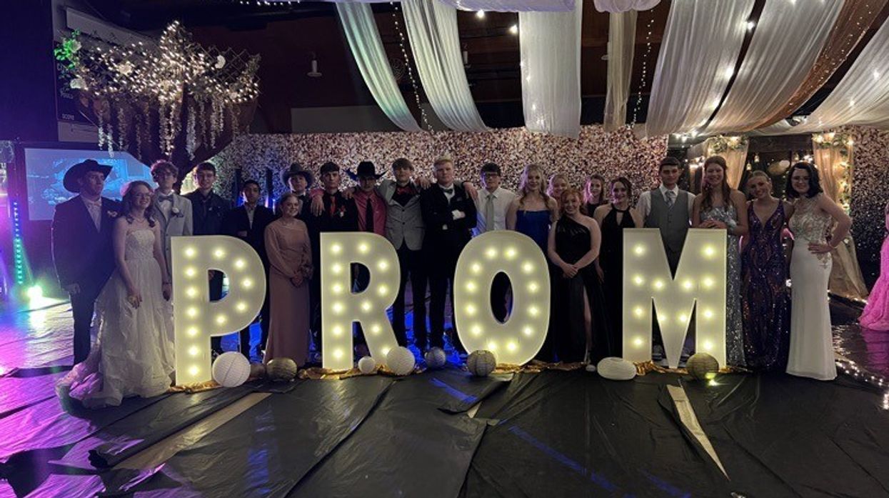 High school students standing near a huge "PROM" sign