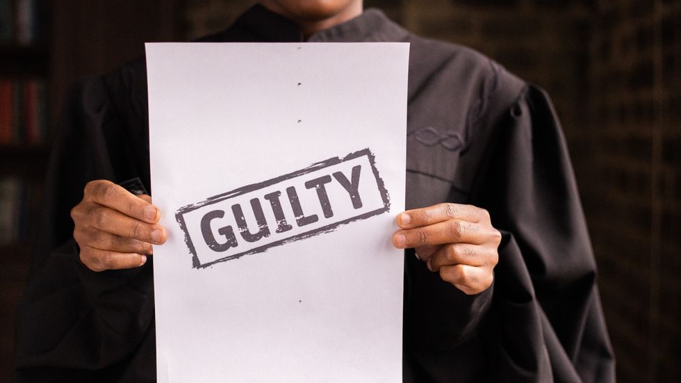 judge holding a paper which says, 'guilty'