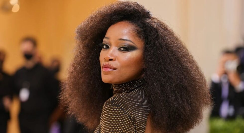Keke Palmer with hair down looking over her shoulder while walking the red carpet.