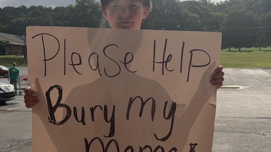 Little boy holding a heartbreaking sign.