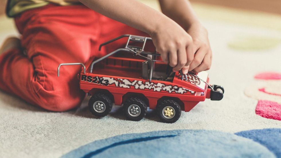 little boy playing with red car