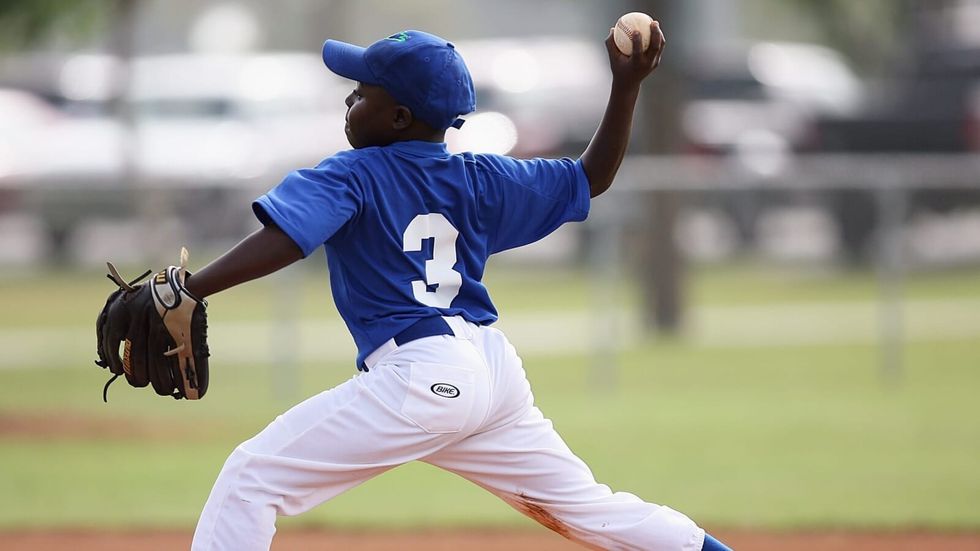 little boy wearing blue and white clothes playing baseball