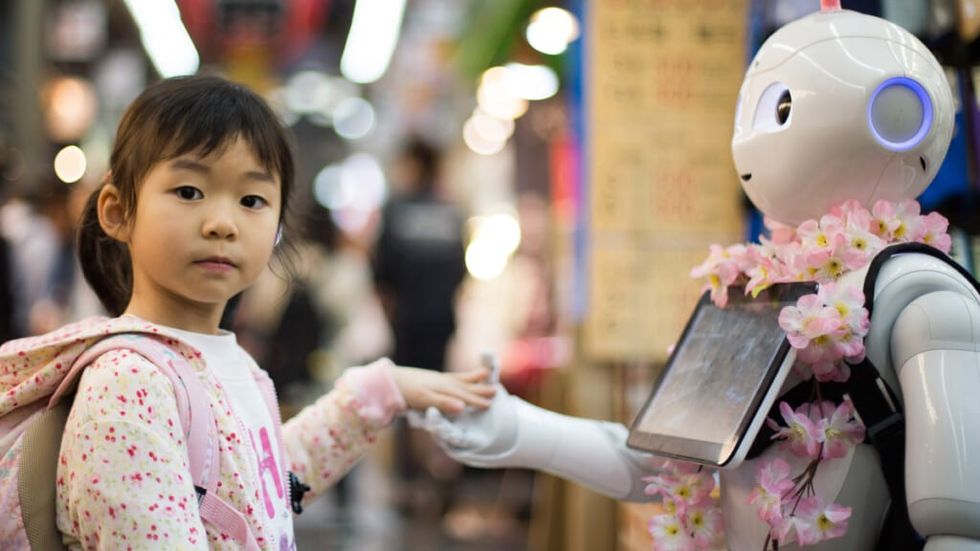 Little girl holds hands with robot 1024x576