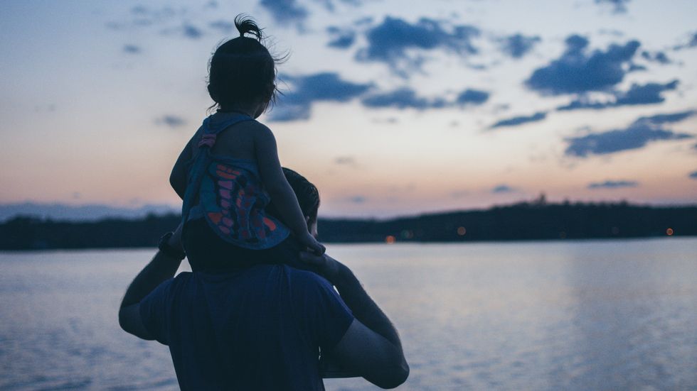 little girl sitting on her dad's shoulders