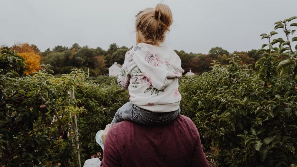 little girl sitting on man's shoulders