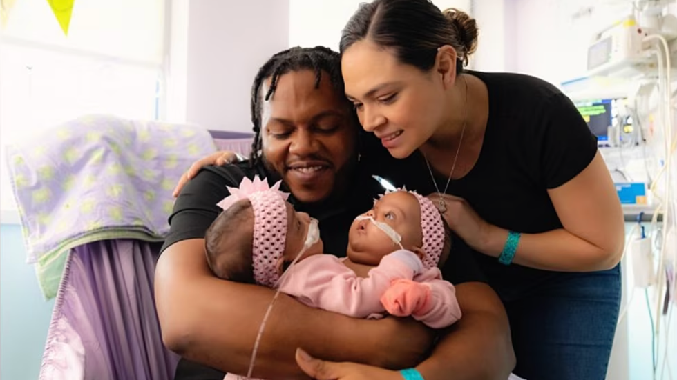 man and woman holding two baby girls in their arms