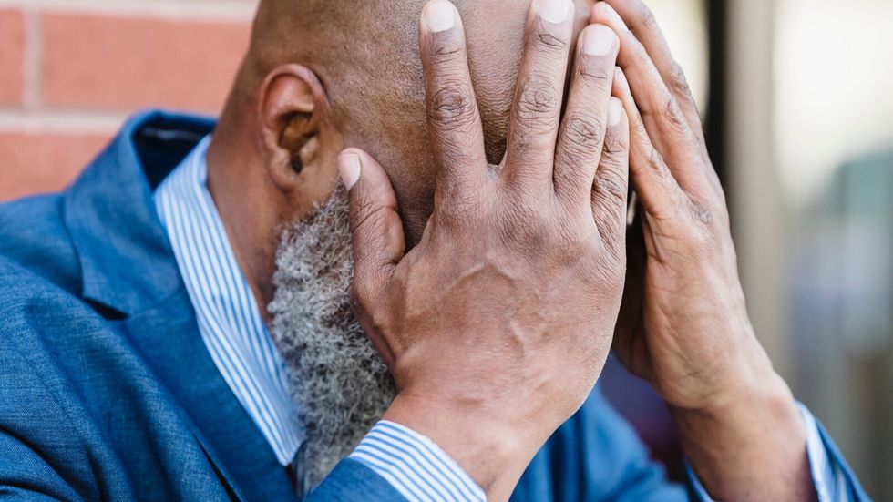 man covering his face with his hands