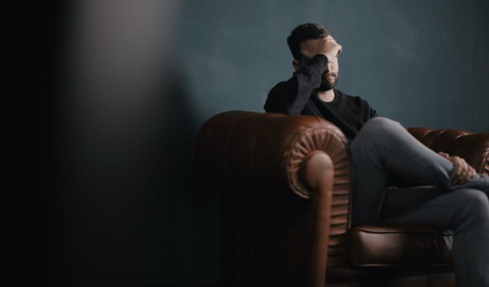 man covers face sitting on couch