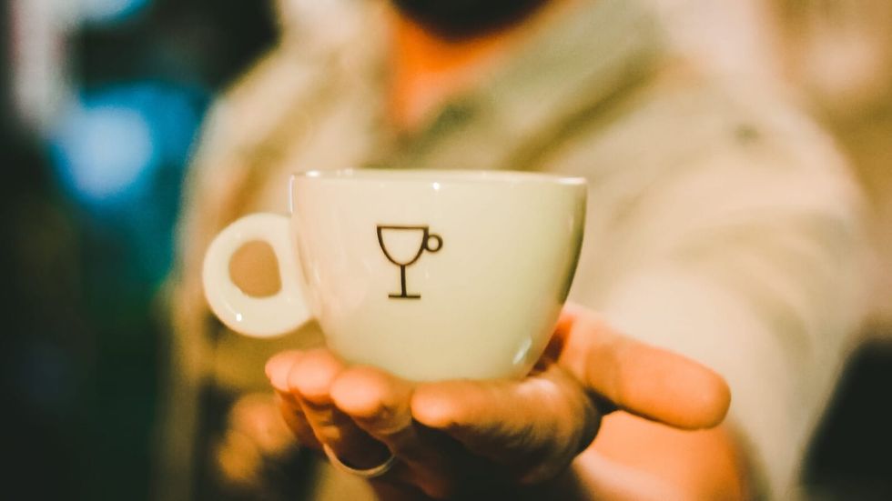 man holding a coffee cup in the palm of his hand