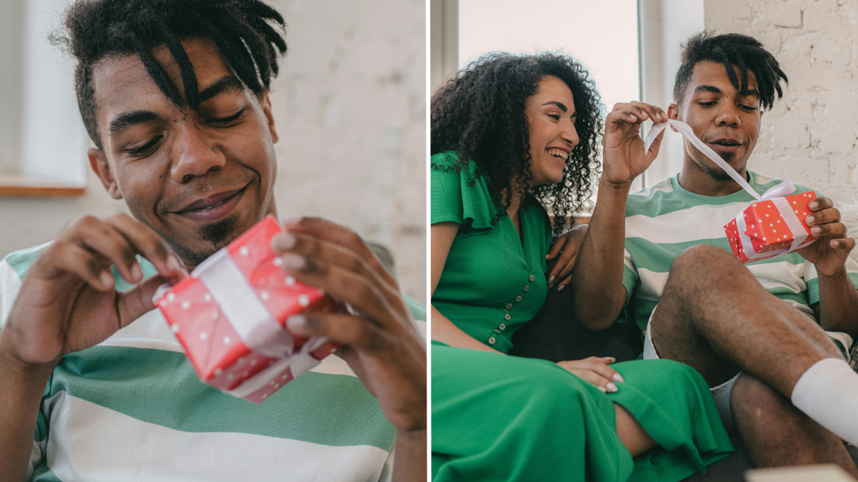 man holding a red gift box and a woman watching a man open a gift