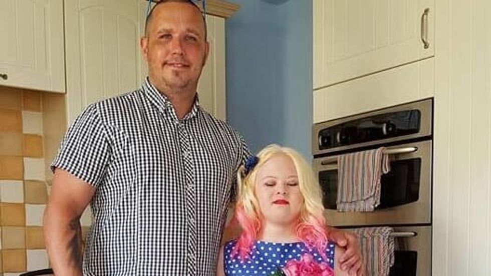 man in a striped shirt standing with a teen girl in a blue dress