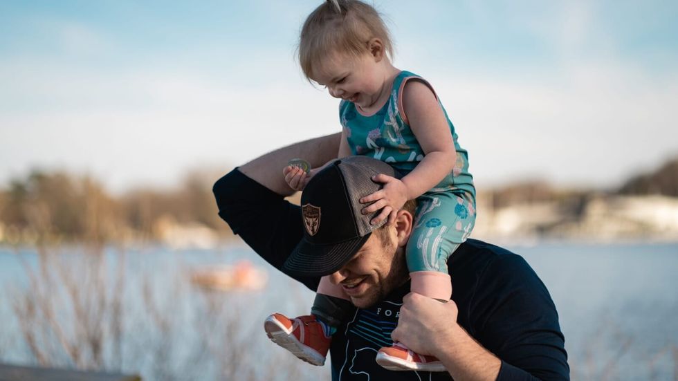 man in black shirt carrying a toddler on his shoulders