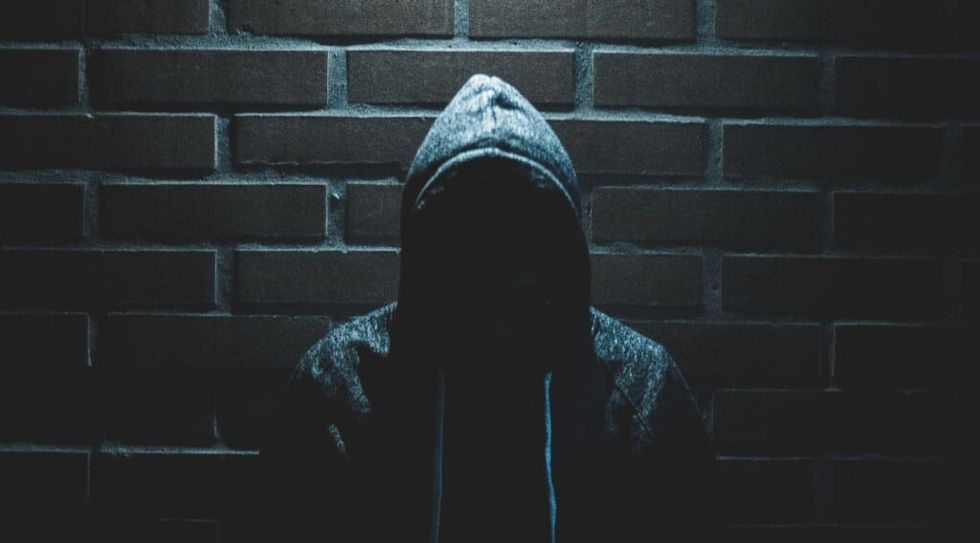 Man in Hoodie against a dark brick wall