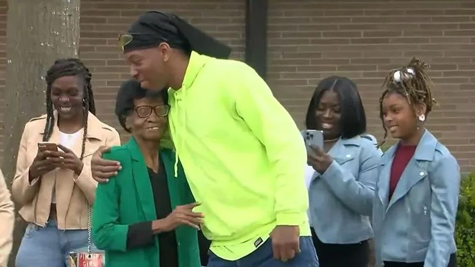 man in neon green jacket hugging elderly woman in green jacket