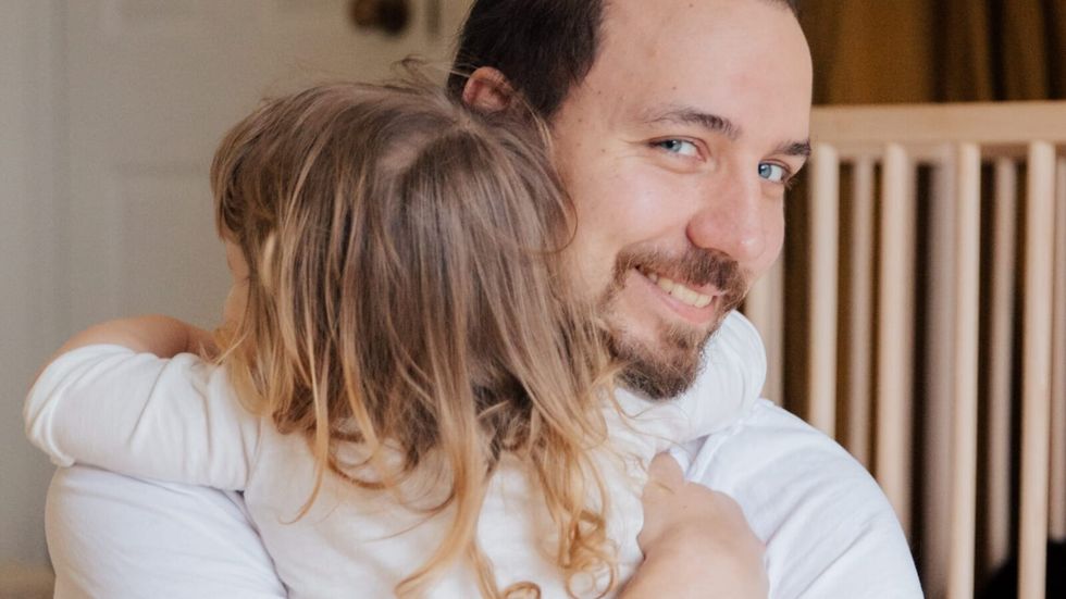 man in white outfit hugging a little girl in a white outfit