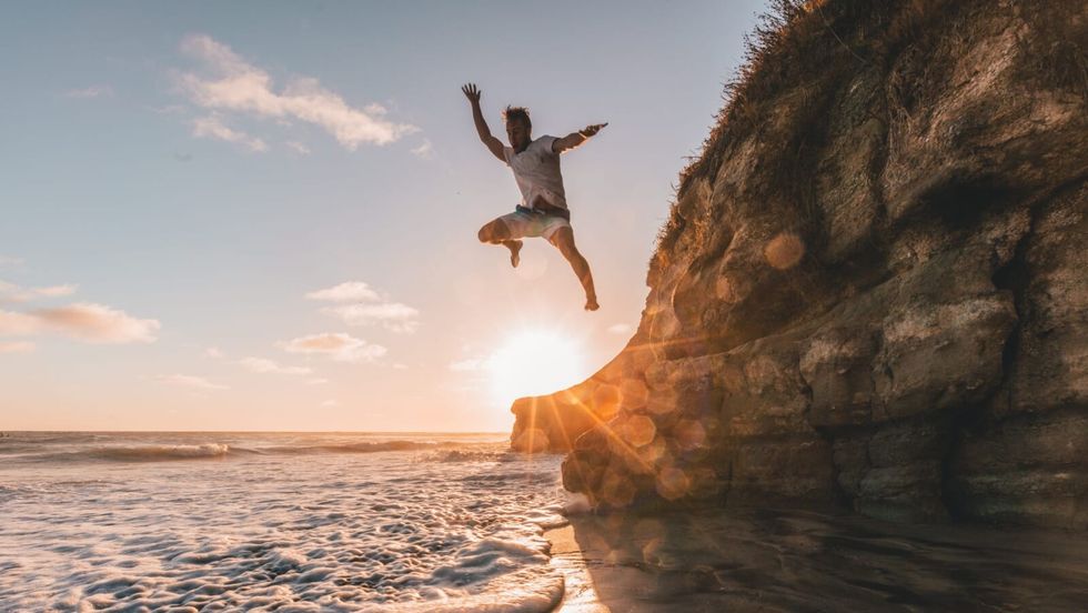man jumping off a cliff into water