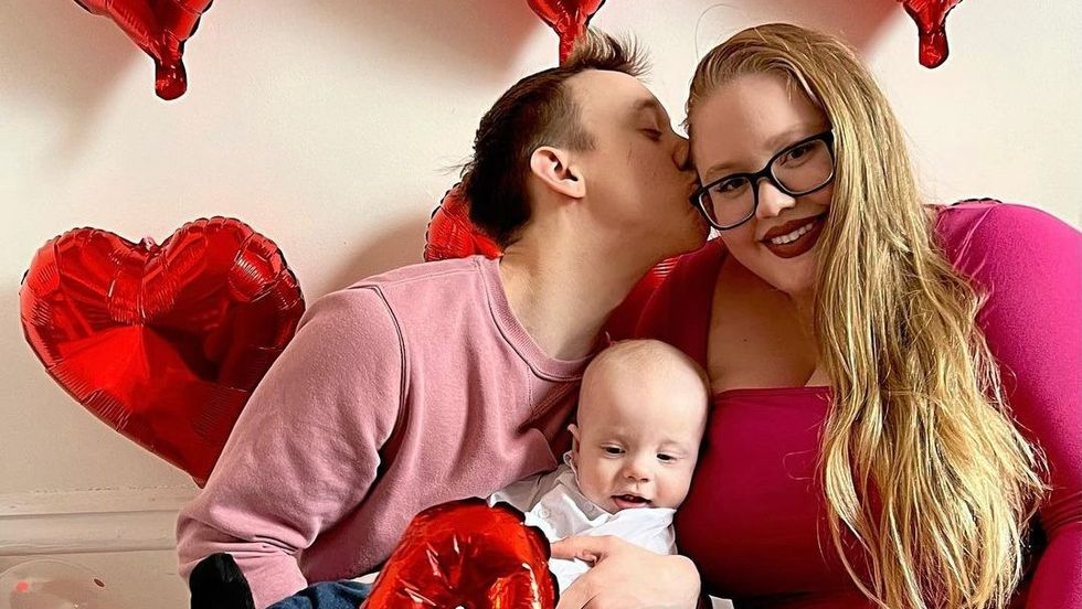 man kissing a woman on the cheek with a baby on his lap