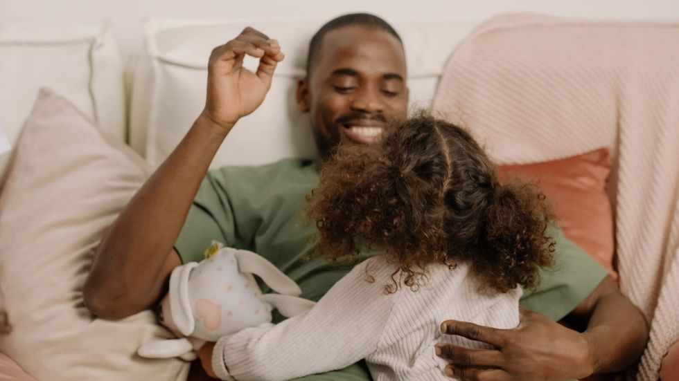 man laughing and playing with his daughter