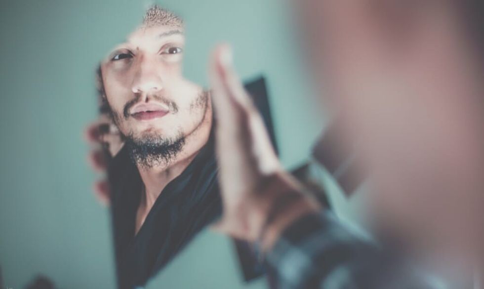 man look into mirror and reflects on his life