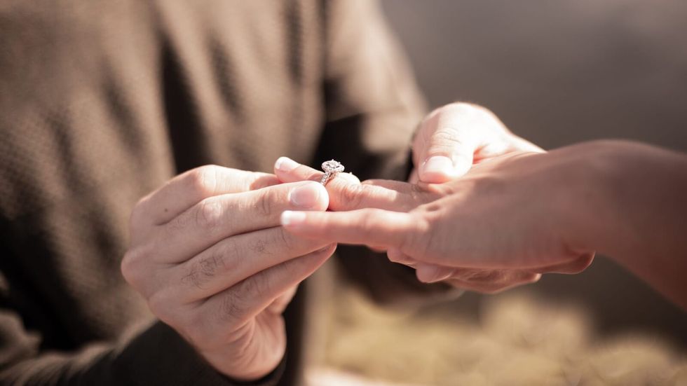 man putting a ring on a woman's finger