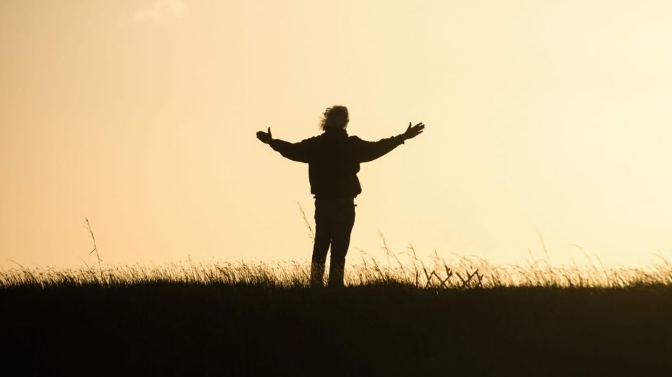 Man's silhouette standing and spreading his hands