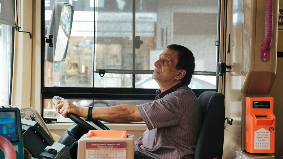 man sitting at the steering wheel, driving a bus