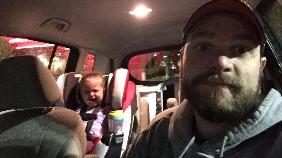 man sitting in a car with a crying baby