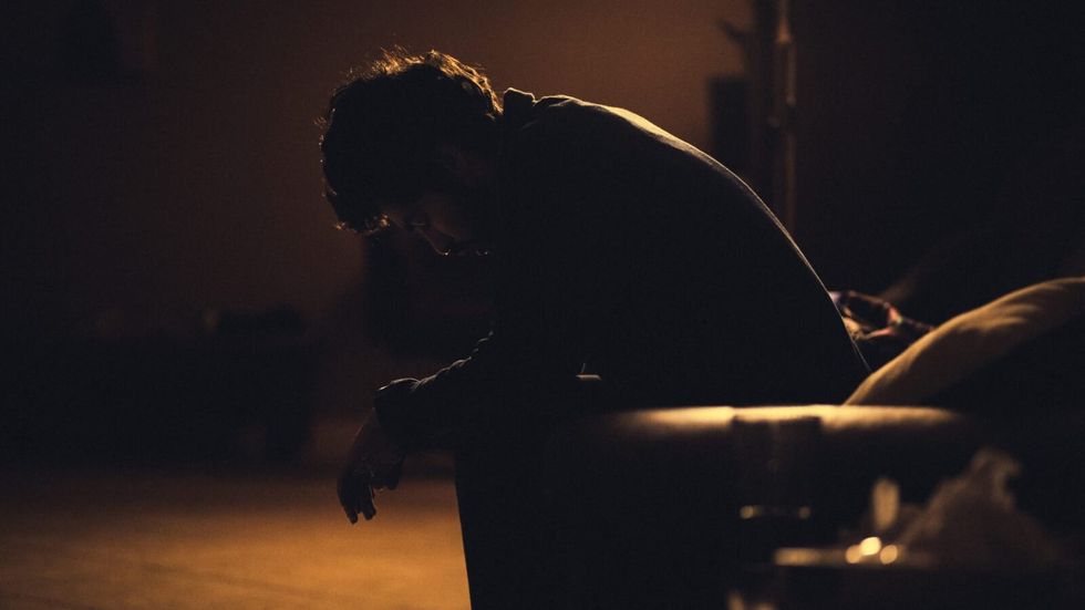 man sitting in the dark with head bent