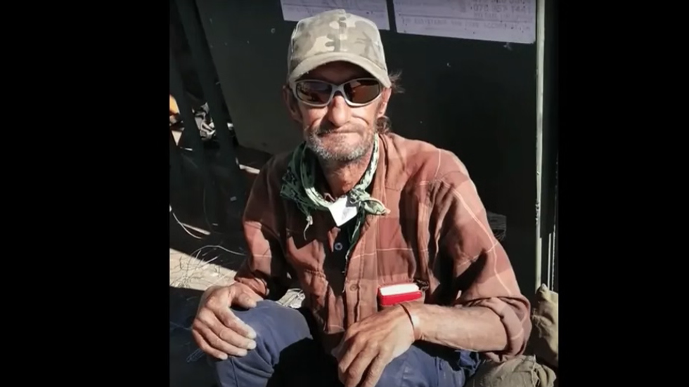 man sitting on the street wearing a cap