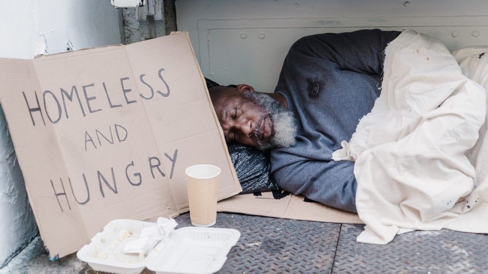 man sleeping on the ground next to a sign reading