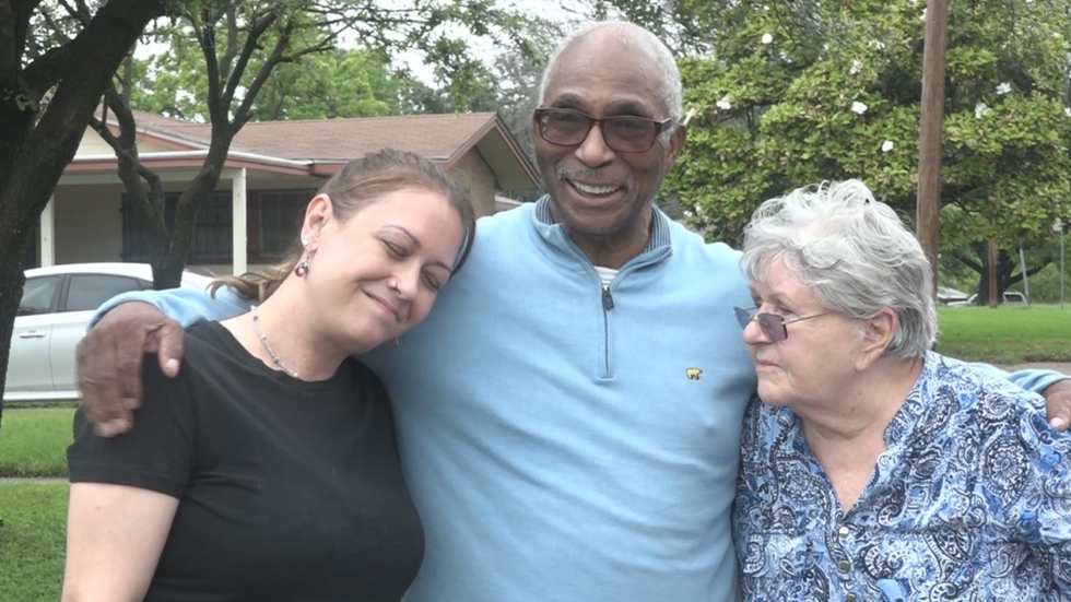 man standing in between a woman wearing a black shirt and an elderly woman