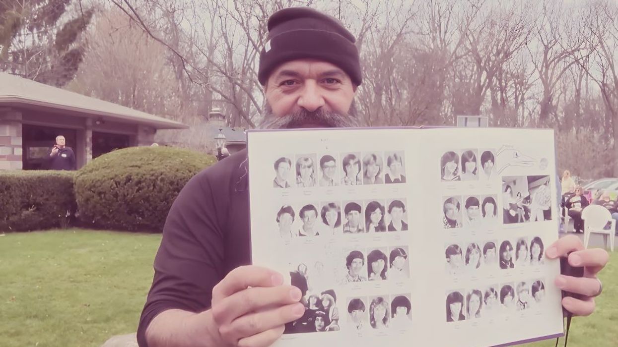 man wearing a beanie holding an open yearbook