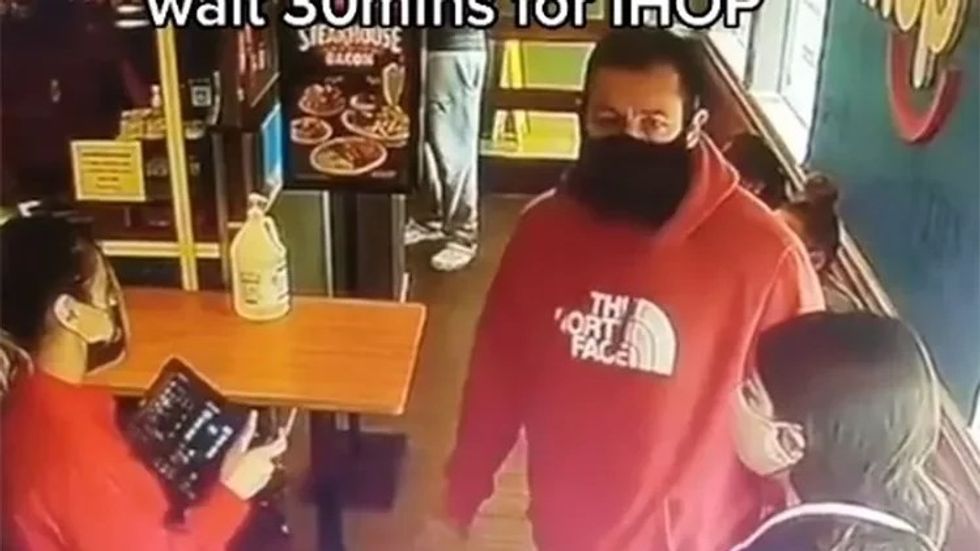 man wearing a red sweatshirt and a black mask