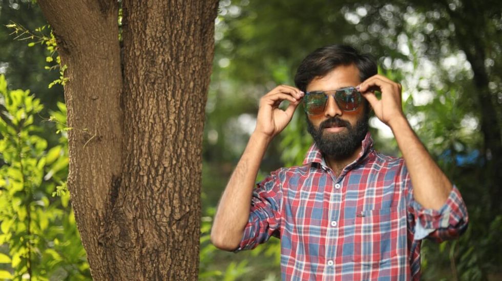 Man with beard putting sunglasses on by Gyan Shahane on Unsplash