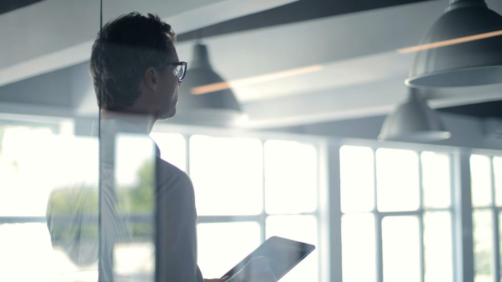 man with glasses holding a tablet and giving a presentation