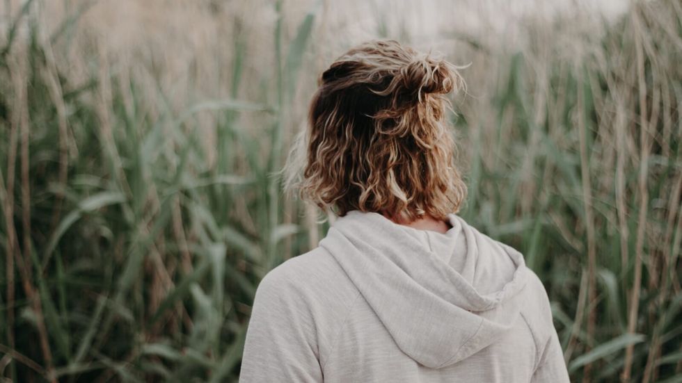 man with long blond hair in a bun wearing an off-white hoodie
