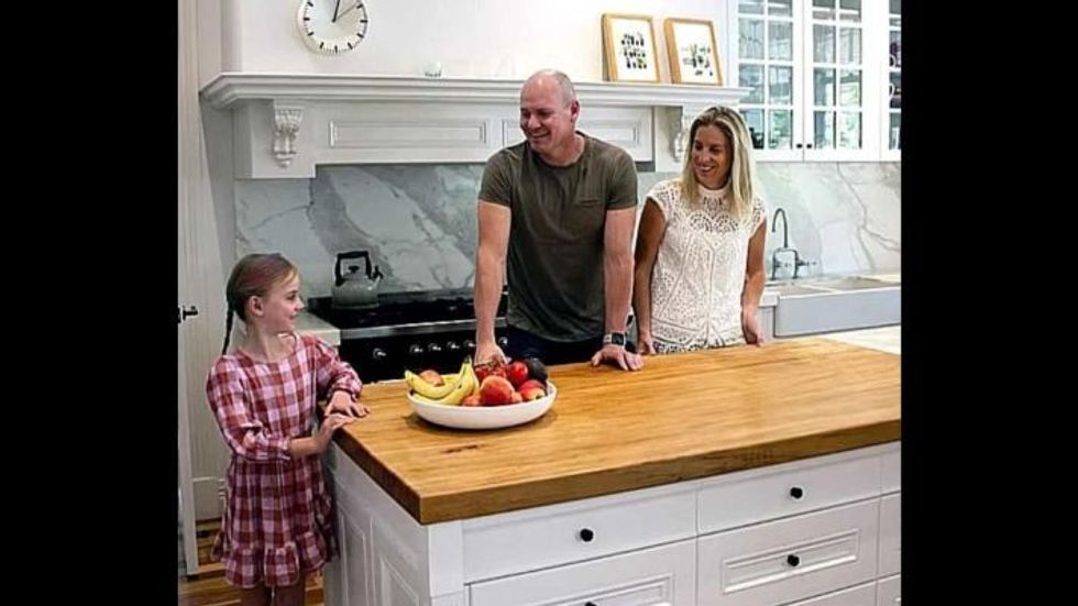 man, woman, and little girl standing in the kitchen