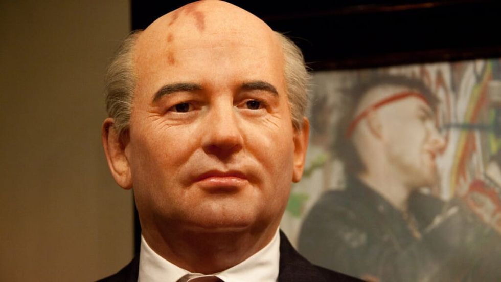 Mikhail Gorbachev in front of a poster of a punk