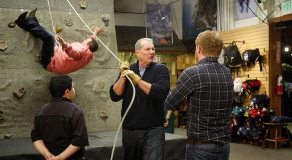 Modern Family: Jay Pritchett letting Cam drop while rock climbing, Mitchell looks on.