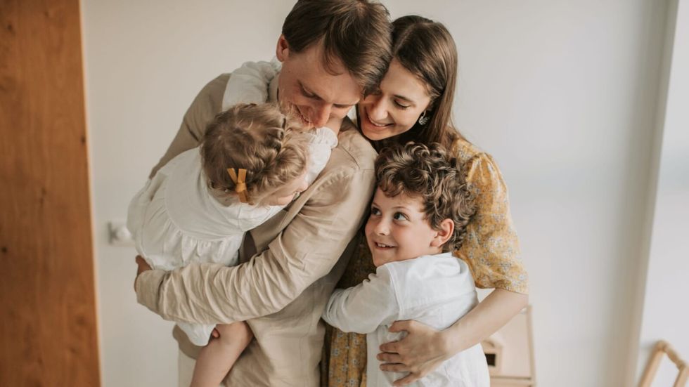 mom and dad hugging their 2 kids