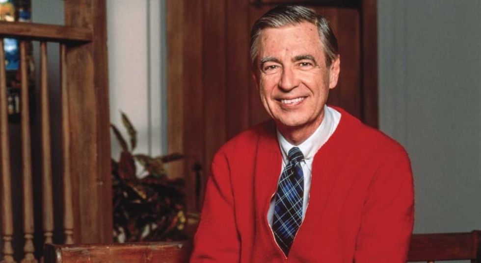 Mr. Rogers smiling at the camera in a red sweater
