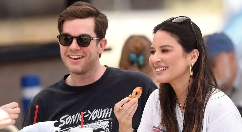 Olivia Munn and John Mulaney sitting at a picnic table and eating.