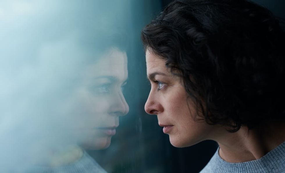 pensive woman looks out window