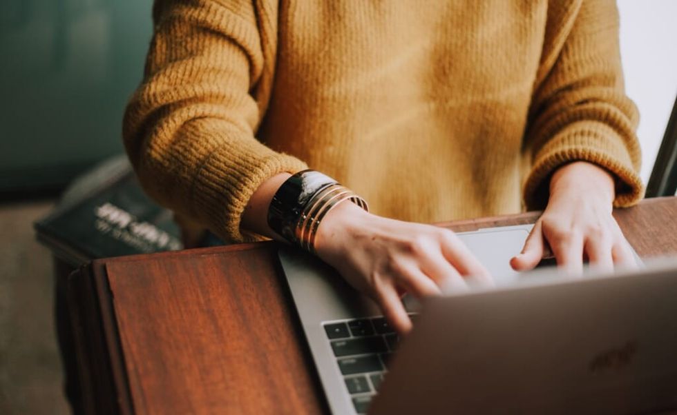 person diligently types on laptop