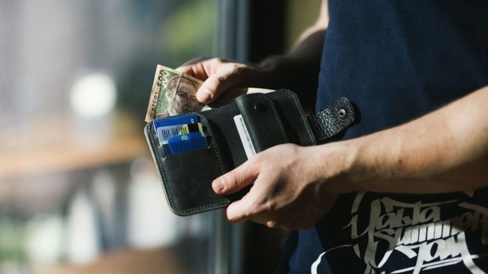 person holding a black wallet with money