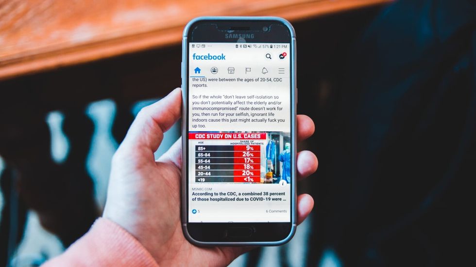 person holding a phone with facebook open on it