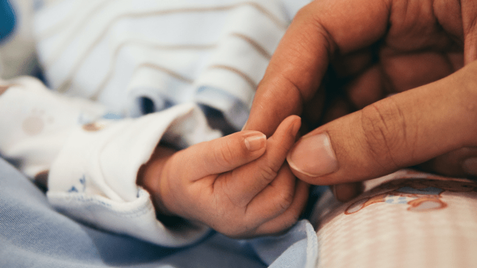 person holding newborn baby's hand