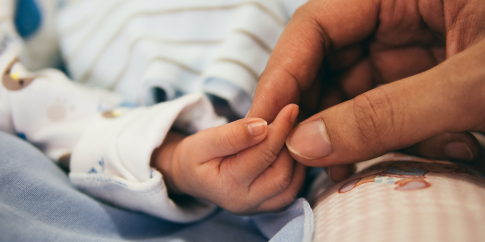 person holding newborn baby's hand