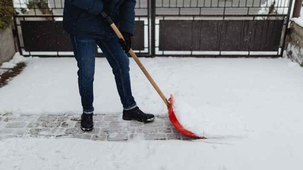 person in a winter jacket shoveling snow